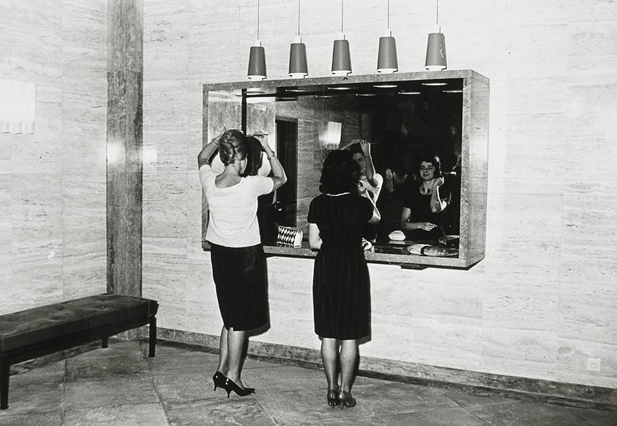 Een dame fixeert het haar voor de Spiegel in de Lobby